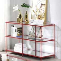 a red shelf with books and vases on it in front of a white wall