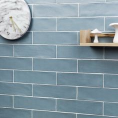 a clock mounted to the side of a blue brick wall next to shelves with mushrooms on them