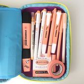 a blue case filled with lots of different types of pens and pencils on top of a table