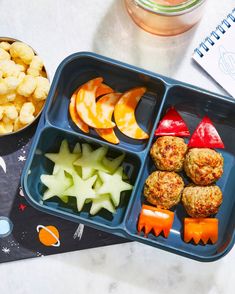 a blue tray filled with food on top of a table next to a bowl of fruit