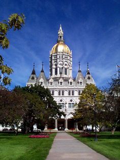 a large white building with a gold dome on it's top and green grass in front