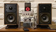 two speakers sitting on top of a wooden table next to a remote control and speaker box