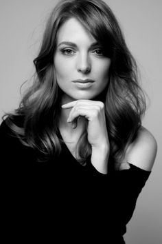 a black and white photo of a woman with her hand on her chin looking at the camera