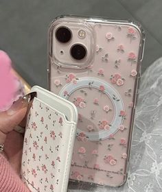 a person holding an iphone case with flowers on it and a wallet in the other hand