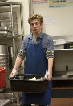 a man in an apron is holding a container