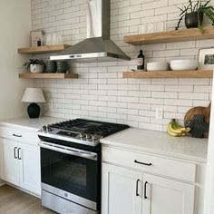 a stove top oven sitting inside of a kitchen next to white cupboards and shelves