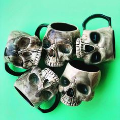 five skull mugs sitting on top of each other with their faces painted to look like they are holding hands