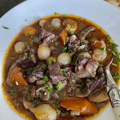 a white plate topped with meat and veggies covered in gravy next to bread