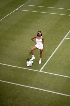 a woman standing on top of a tennis court holding a racquet and ball