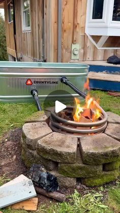 a fire pit sitting on top of a grass covered field next to a metal tub