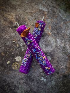 two purple candles with sprinkles on them are sitting on the ground next to each other