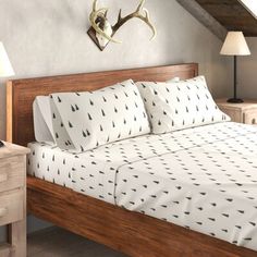 a bed with white sheets and black arrows on it next to a night stand, two nightstands and an antler head