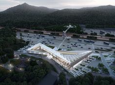 an aerial view of a building surrounded by trees and parking lot with mountains in the background