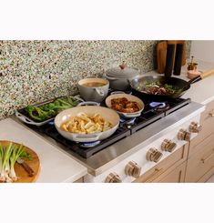 a stove top with bowls and pans on it next to other cooking utensils