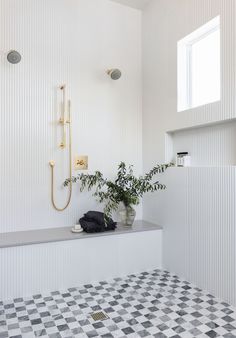 a bathroom with a checkered tile floor and white walls, along with a plant in the corner