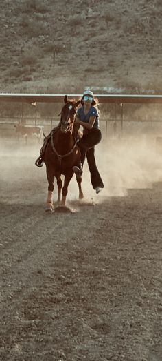 two people riding horses in an arena with dust coming from the ground and dirt behind them