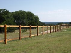 a wooden fence in the middle of a grassy field