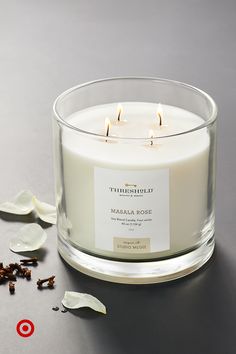 a white candle sitting on top of a table next to some dried flowers and petals