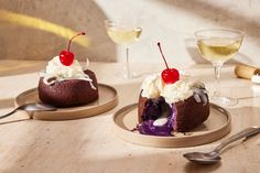 two desserts on plates with wine glasses in the background