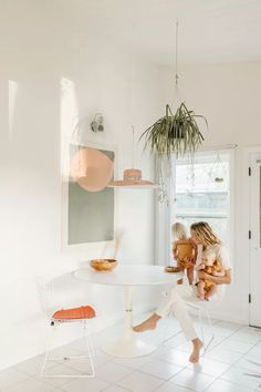 a woman sitting at a table in a white room