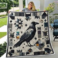 a woman holding up a quilt with a crow on it