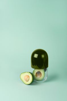 an avocado cut in half sitting on top of a green surface by luke vandermeer for stockstuffs