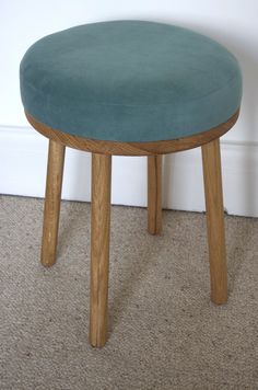 a small stool sitting on top of a carpeted floor next to a white wall