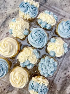 cupcakes with blue and white frosting arranged in a square tray on a table