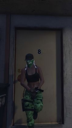 a woman in camo pants and a black top is standing by a door with her hands on her hips