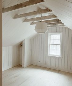 an empty room with white walls and wooden beams