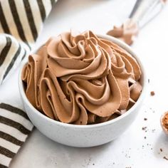 a white bowl filled with chocolate frosting on top of a table