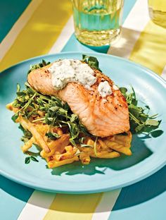 a blue plate topped with fish and french fries on top of a striped table cloth