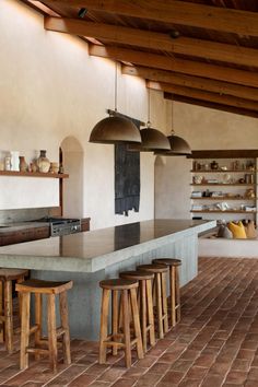 a kitchen with several stools in front of an island and shelves on the wall