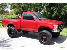 a red pick up truck parked in front of some trees