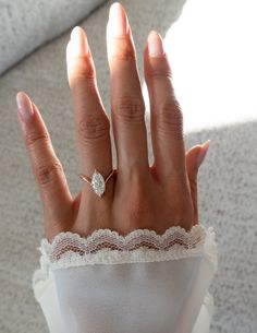 a woman's hand with an engagement ring on top of her wedding band and lace