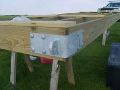 a truck is parked in the grass next to a wooden structure with metal studs on it