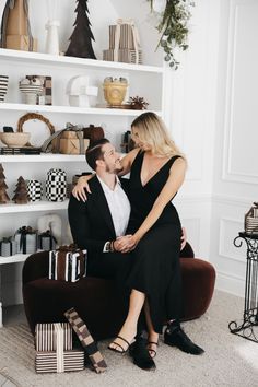 a man and woman are sitting on a chair in front of shelves with christmas decorations