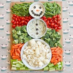 a platter filled with veggies, cauliflower, carrots and snowman faces