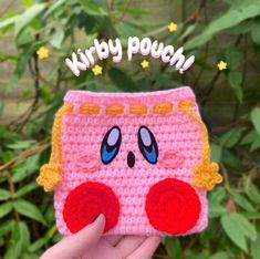 a hand holding up a pink crocheted purse with an image of donald duck on it