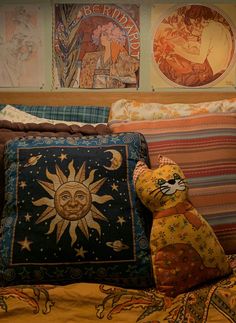 a stuffed animal sitting on top of a bed next to pillows and paintings above it