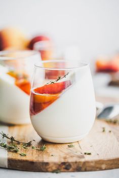 a glass filled with liquid sitting on top of a wooden cutting board next to fruit