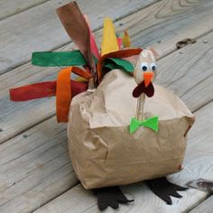 a paper bag with a turkey in it on a wooden table next to carrots