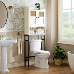 a white toilet sitting next to a sink and a bath tub in a bathroom under a mirror