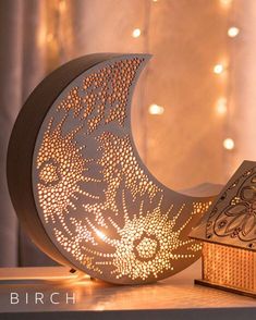 a wooden box sitting on top of a table next to a lit up half moon