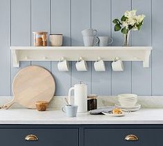 a kitchen with blue cabinets and white counter tops is pictured in this image, there are coffee mugs on the shelves