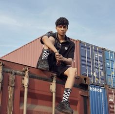 a young man sitting on top of a shipping container