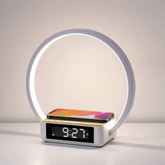 an alarm clock with a cell phone on it's display in front of a white background