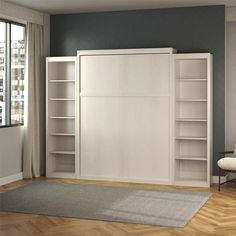 a living room with white bookcases and a gray rug on the wooden floor