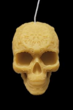 a yellow candle with a skull on it's side and a white string hanging from the top