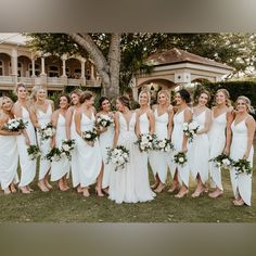 a group of women standing next to each other in front of a house and holding bouquets